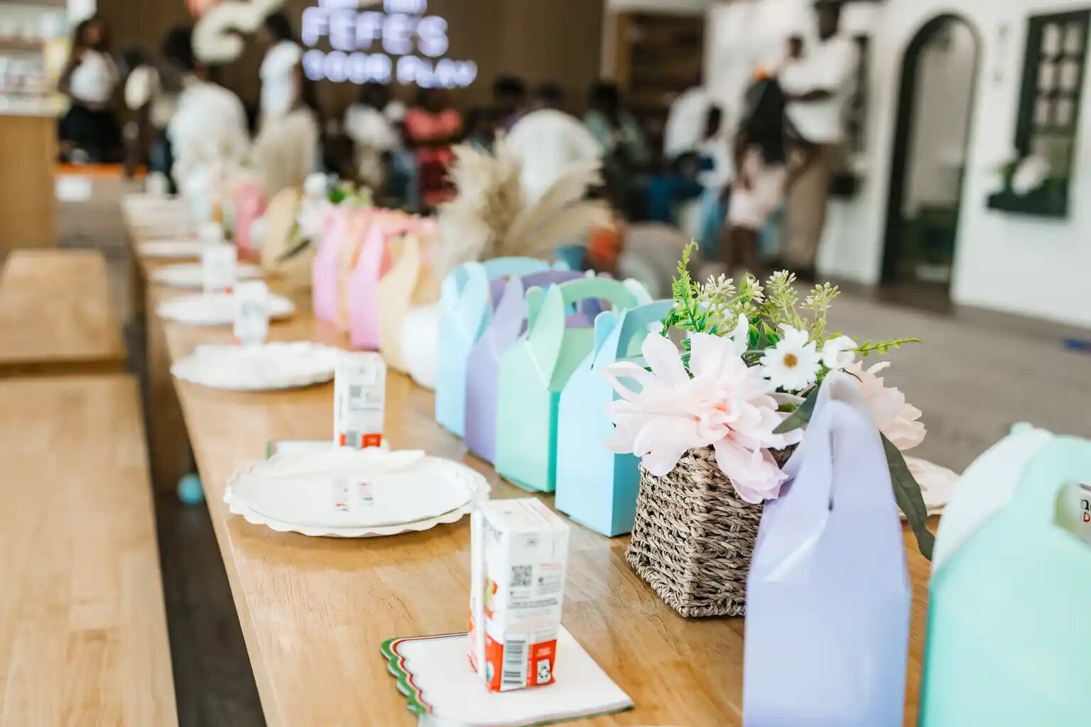 Children's party table styled with pastel favor boxes and fresh florals