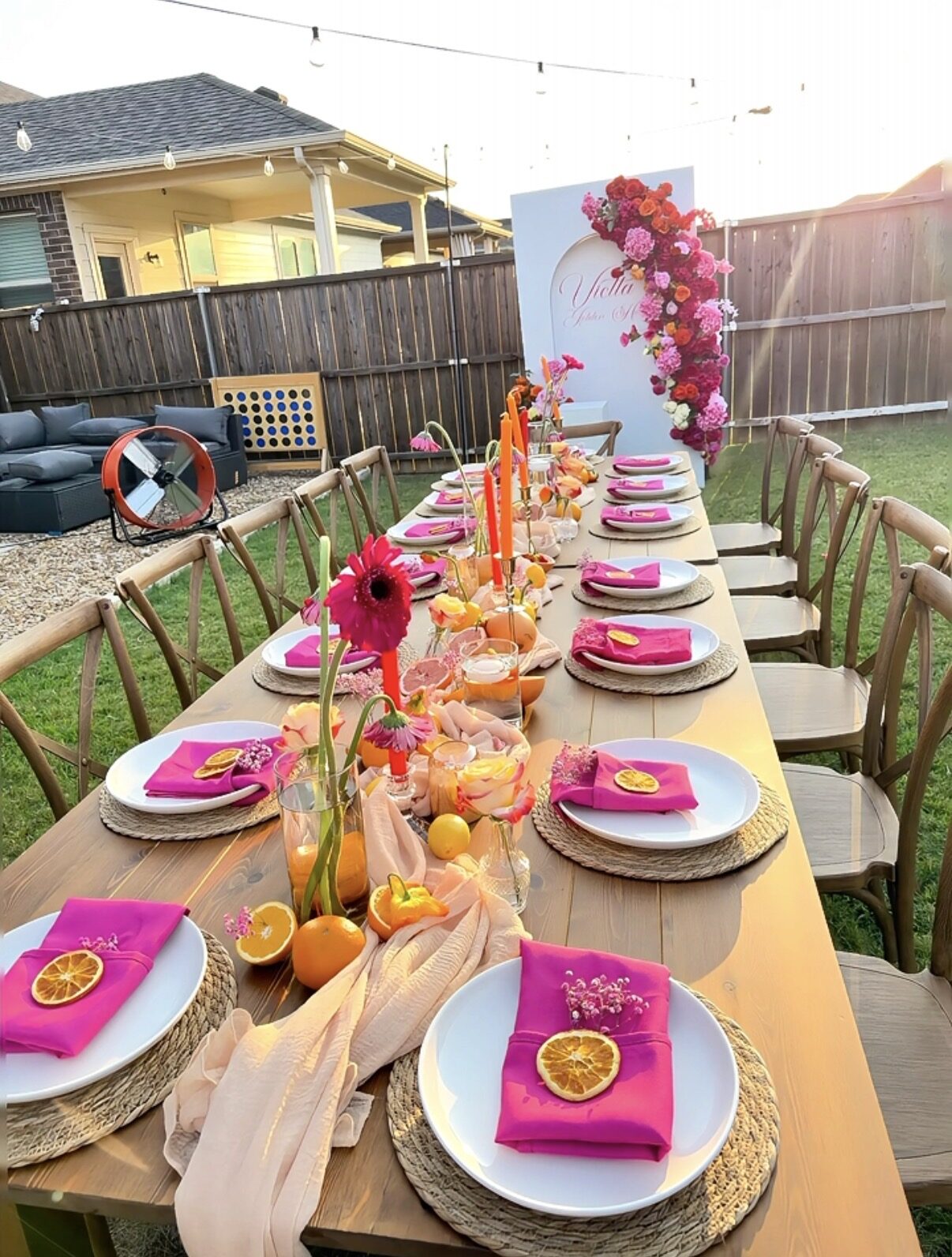 Long outdoor tablescape at golden hour with pink and orange florals, styled by Bon Paradise